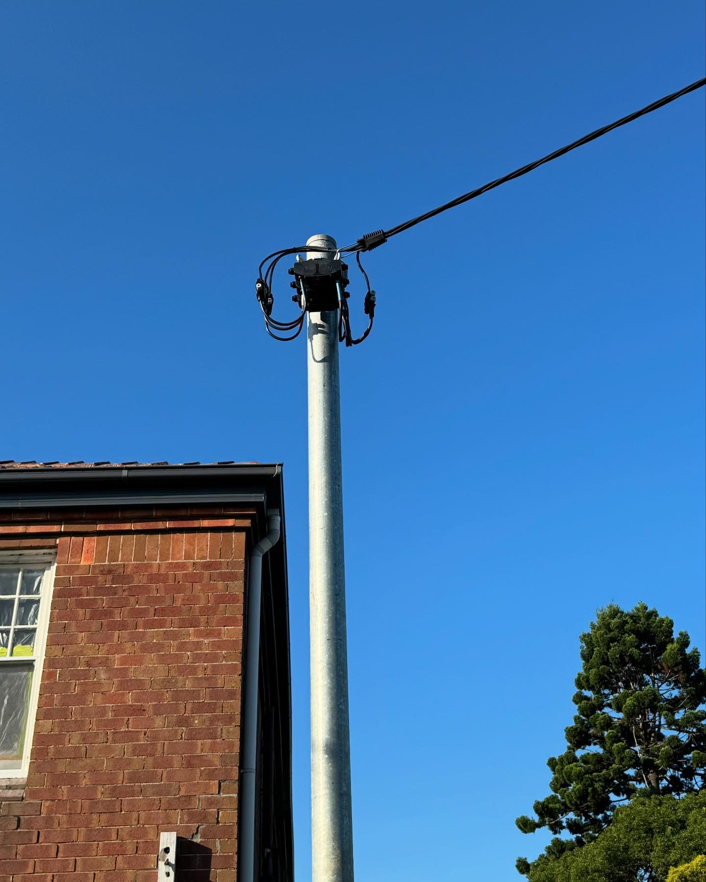 A new galvanised private pole and service line beside a brick home