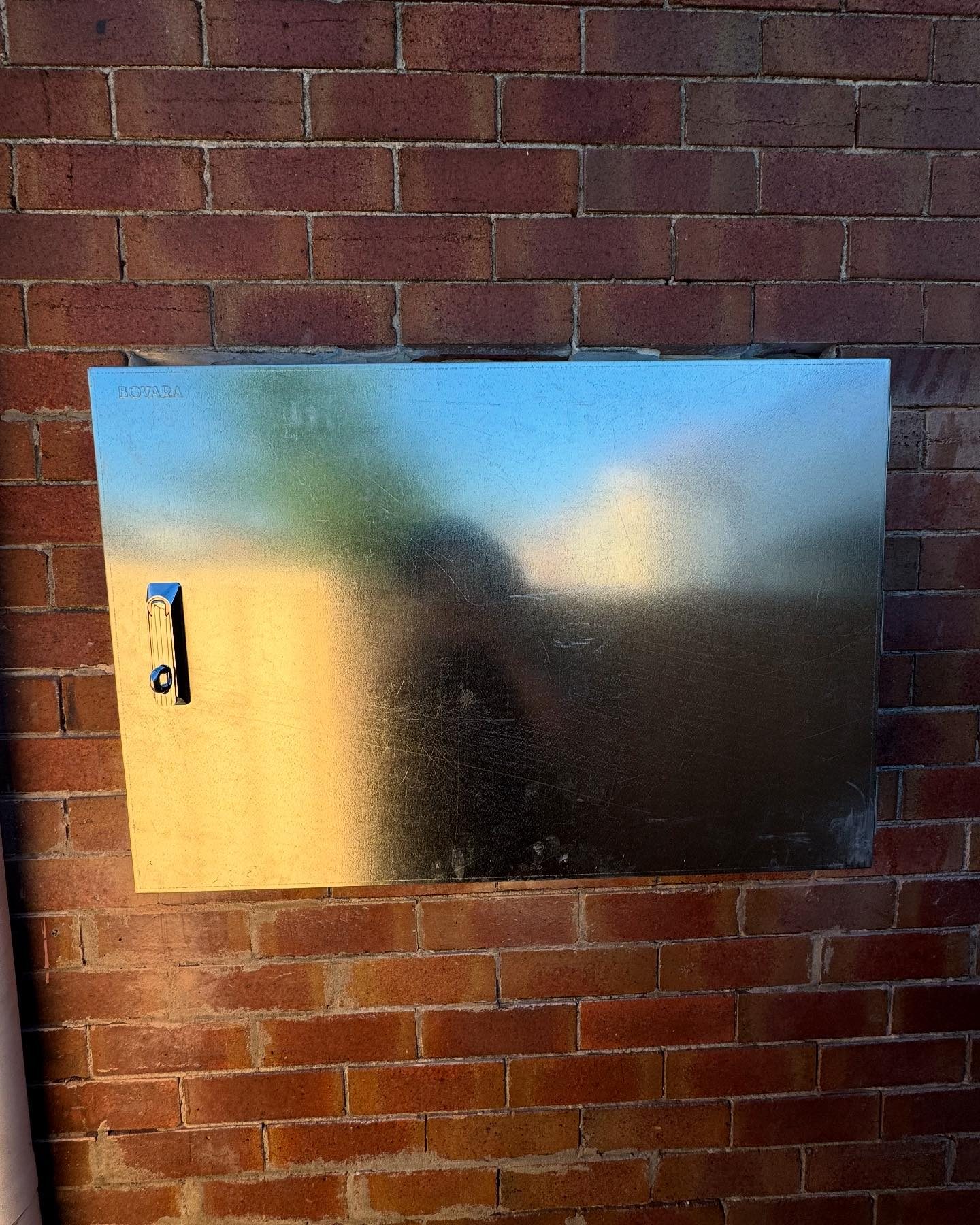 A burnt out switchboard door on a brick wall, the result of an electrical fault