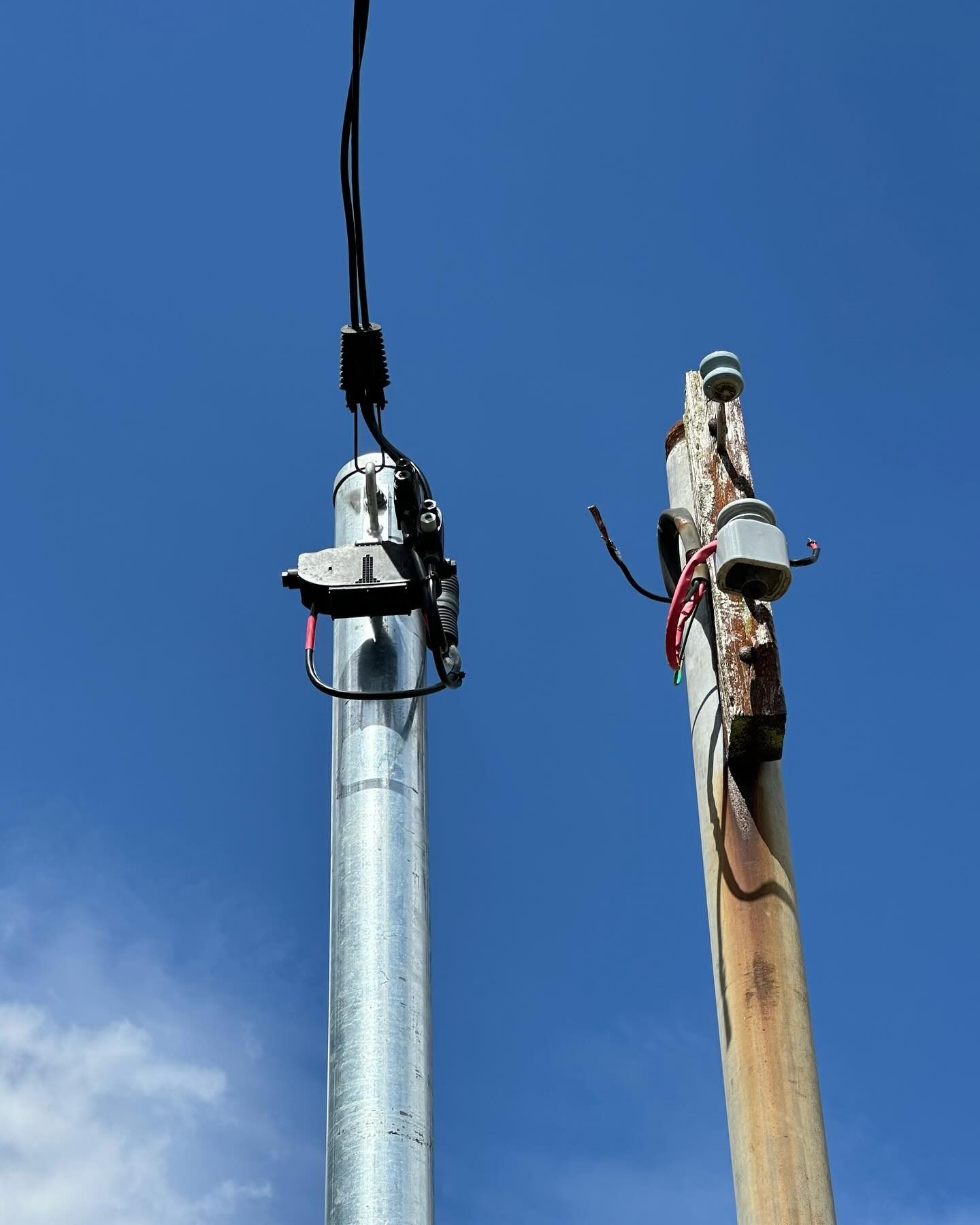 A new galvanised power pole installed beside the old timber pole it replaced, with the service line reattached