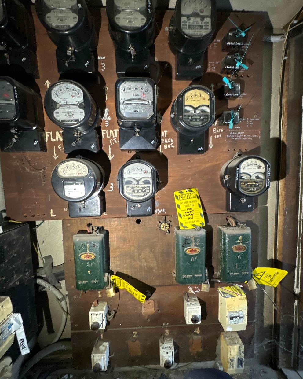 A wall of analogue electricity meters in a commercial switchroom