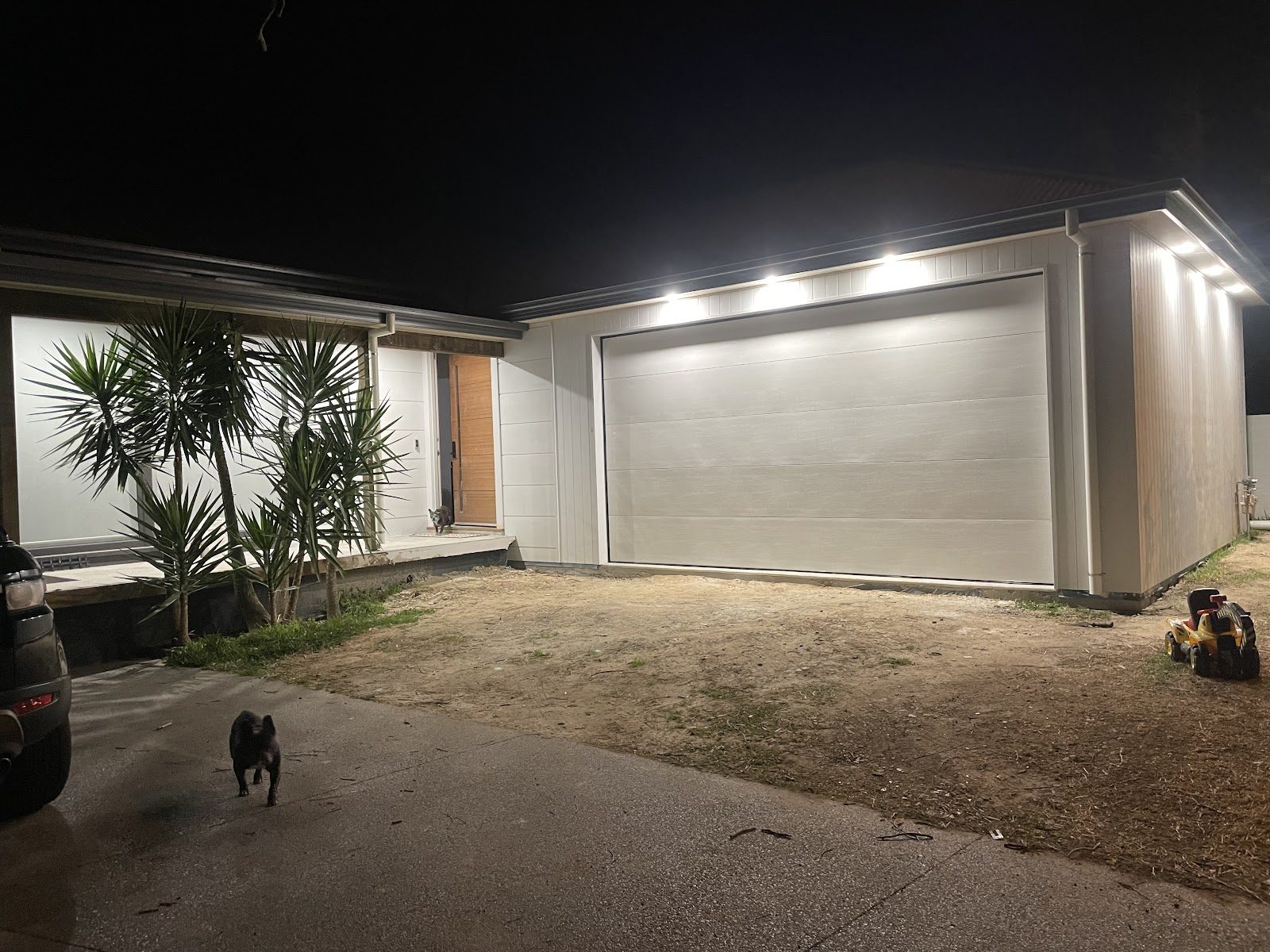 A home at night with new soffit downlights lighting the front of the house and garage